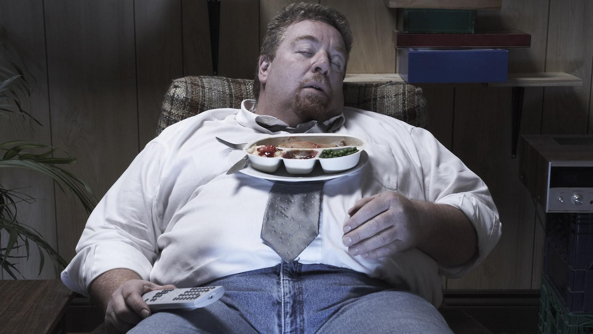 Толстый радуется. Толстый человек в кресле. Упитанный мужчина в кресле. Толстяк с едой.