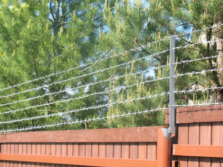 Ограждение из колючей проволоки на забор
