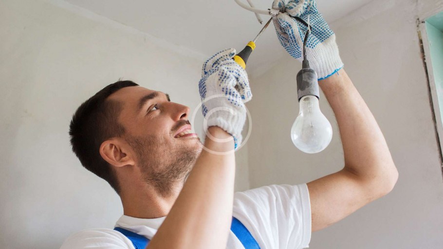 Электрик вкручивает лампочку