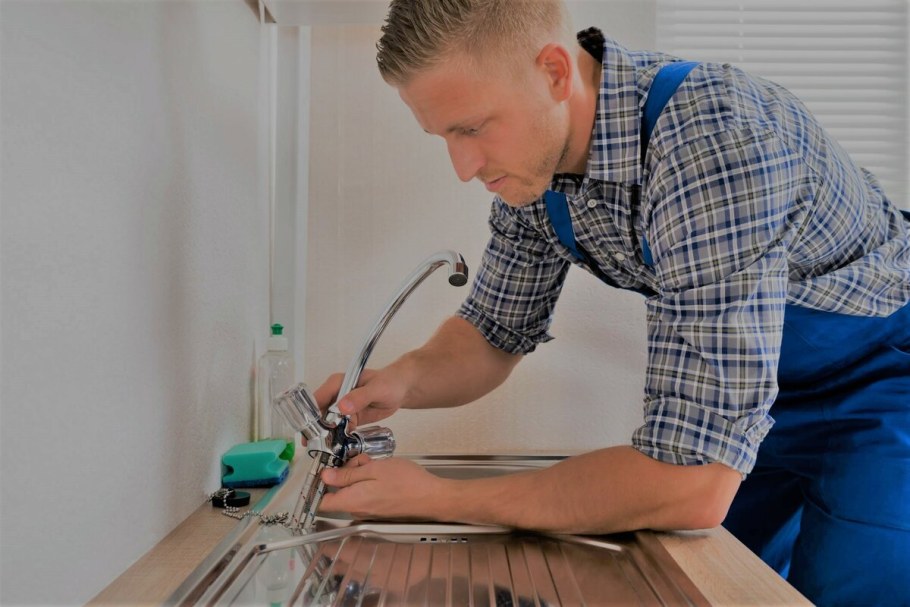 Сантехник чинит кран на кухне