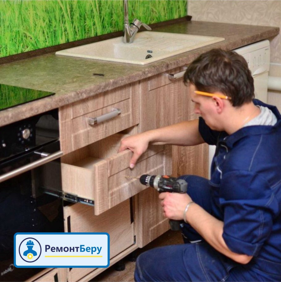 Рабочий собирает кухню