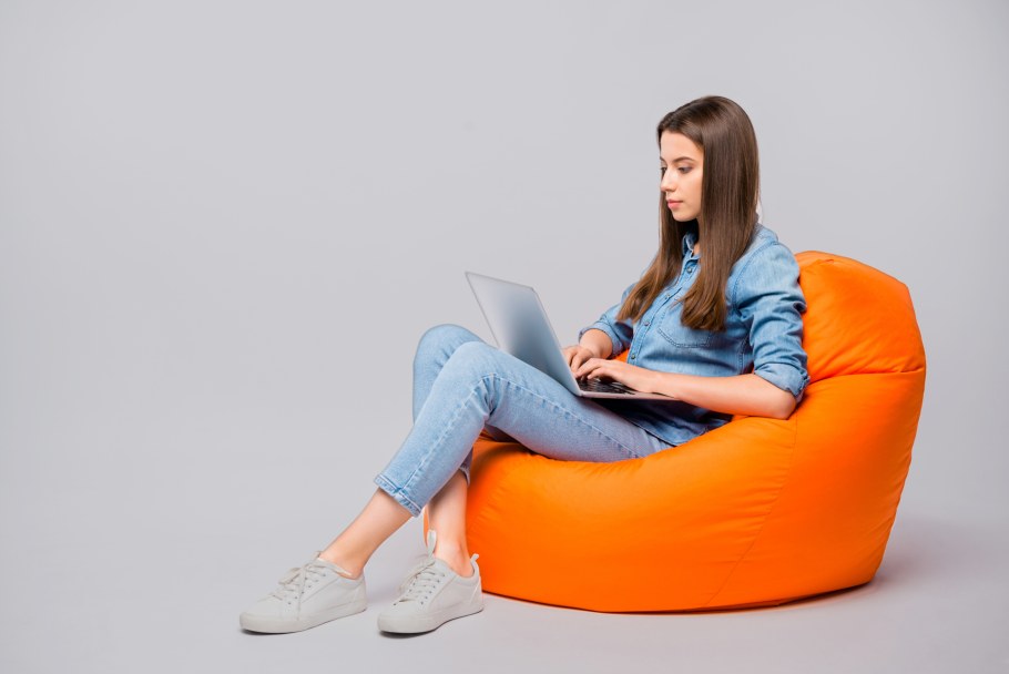 Девушка сидит в кресле сбоку