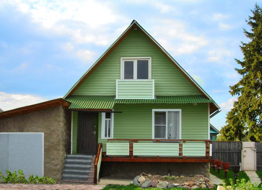 Деревенский дом обшитый сайдингом зеленый