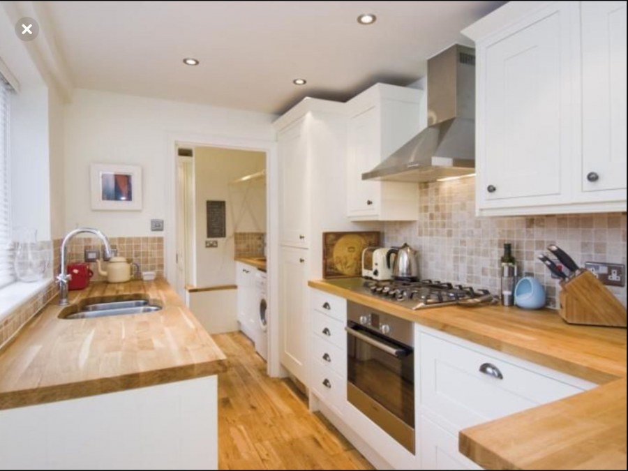 Белая кухня с красным фартуком и деревянной столешницей