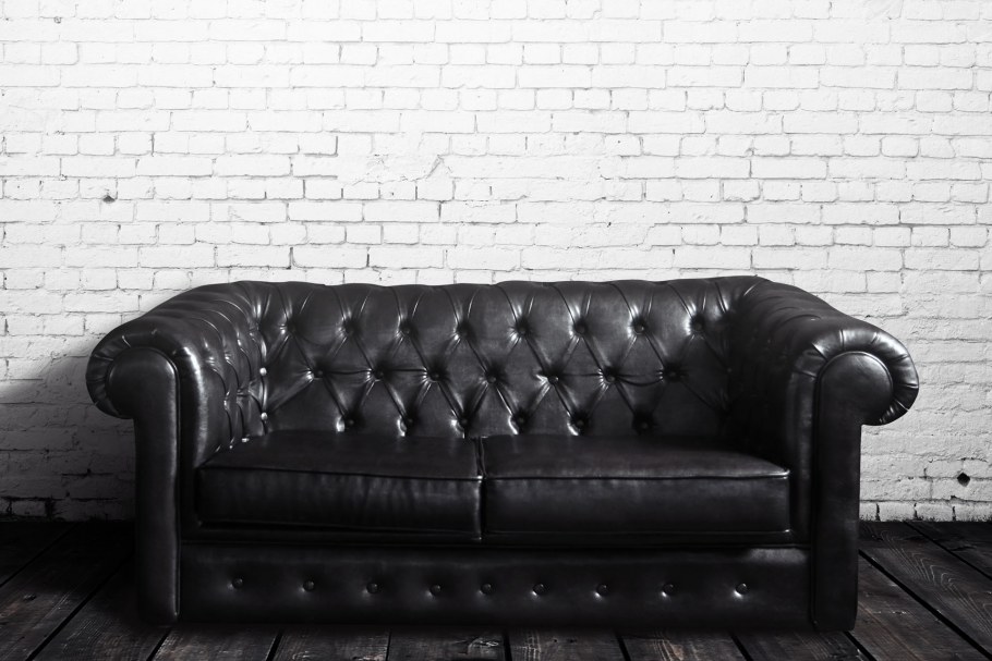 Кожаный диван на фоне кирпичной стены