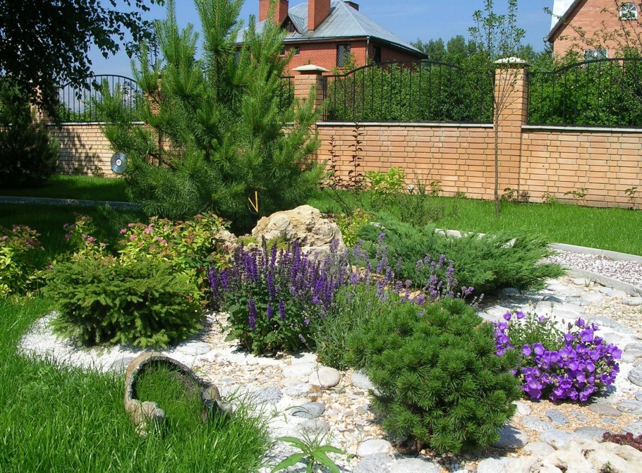 Клумба из хвойников в углу забора