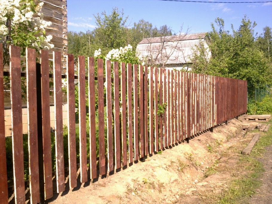 Деревянный забор с железными столбами