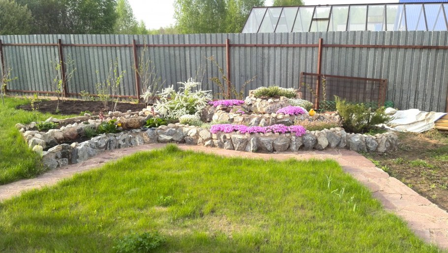 Клумба вдоль забора с альпийской горкой