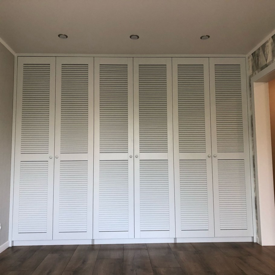 Шкаф с жалюзийными дверцами в интерьере спальни